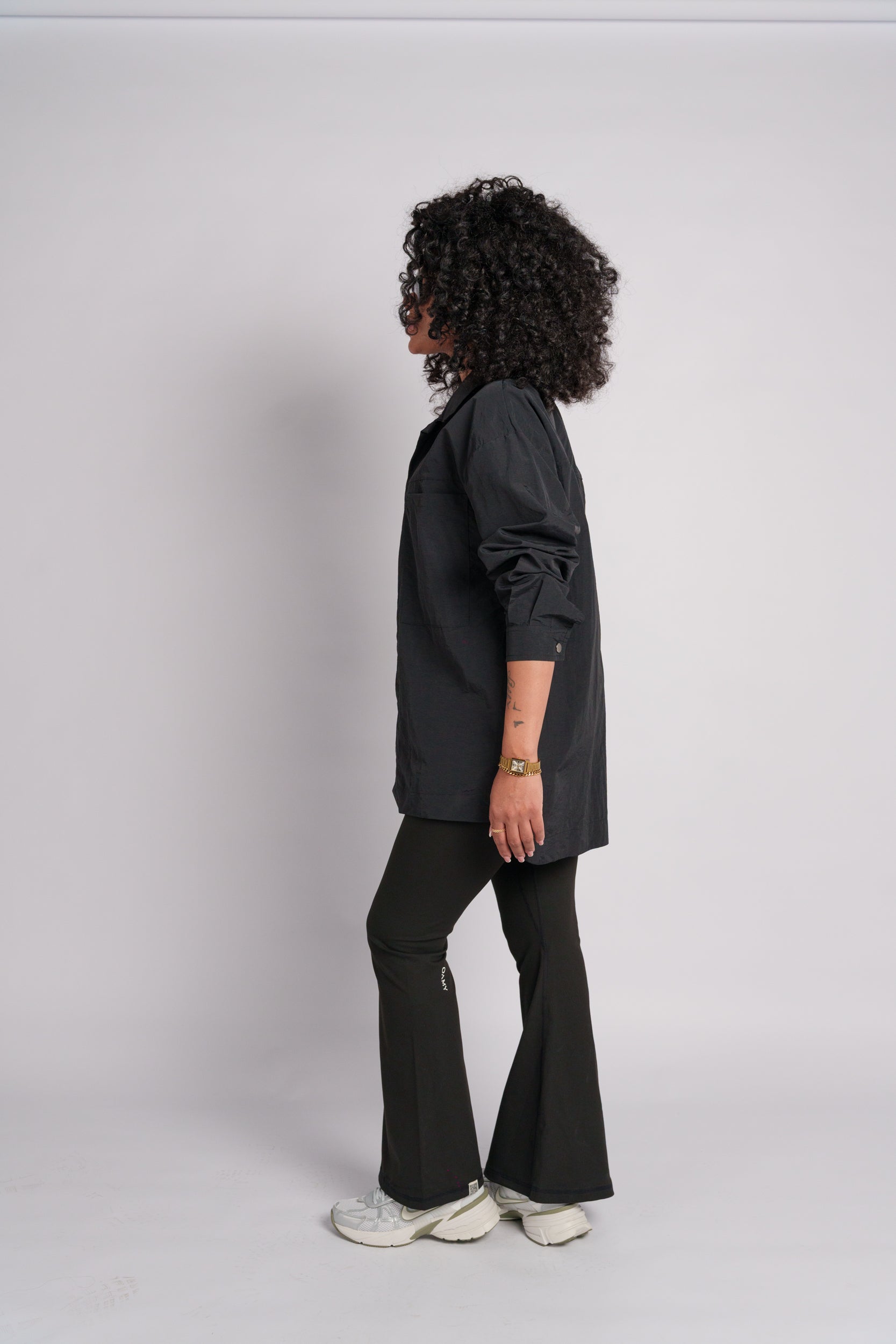 Woman wearing a black crop top with black flared pants and black shirt.