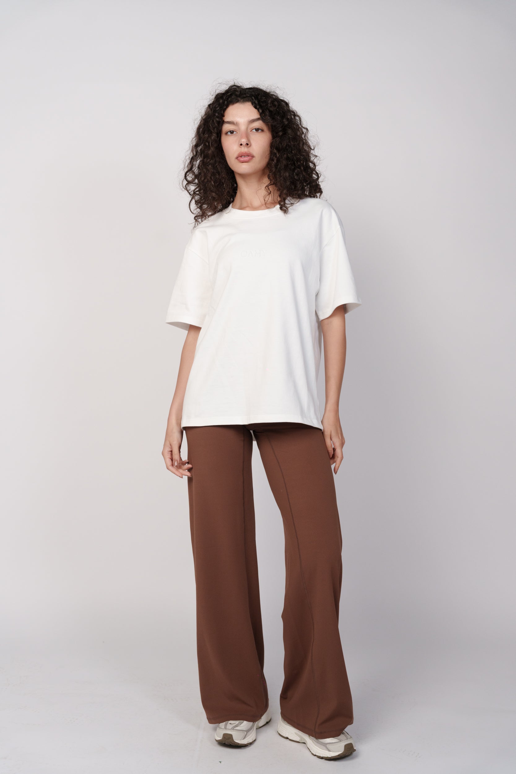 Woman wearing a white top and brown pants on a white background