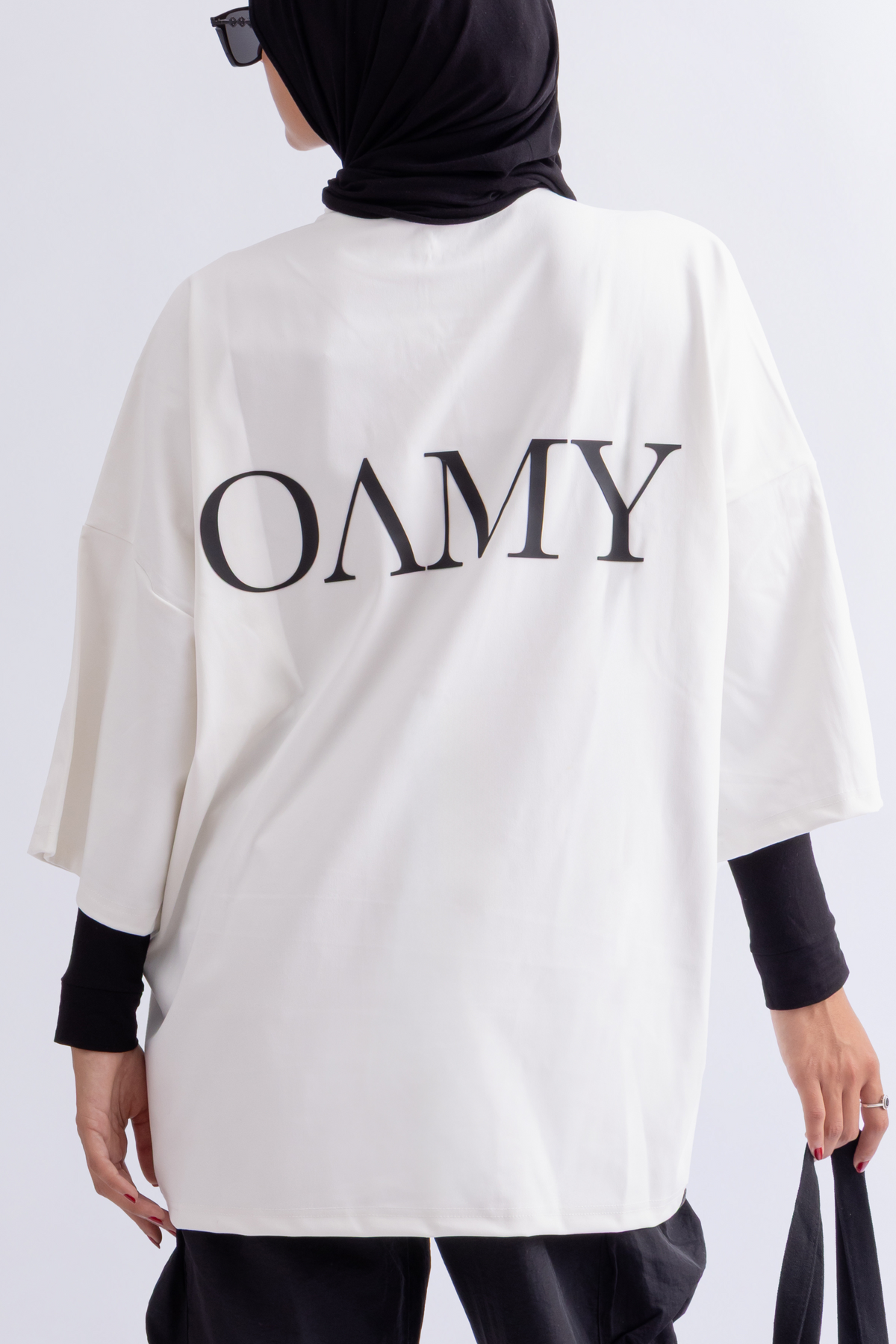 Model wearing the OAMY Super Oversized Soft Skin T-Shirt in White with black Cargos and a black headscarf, holding a black tote bag.