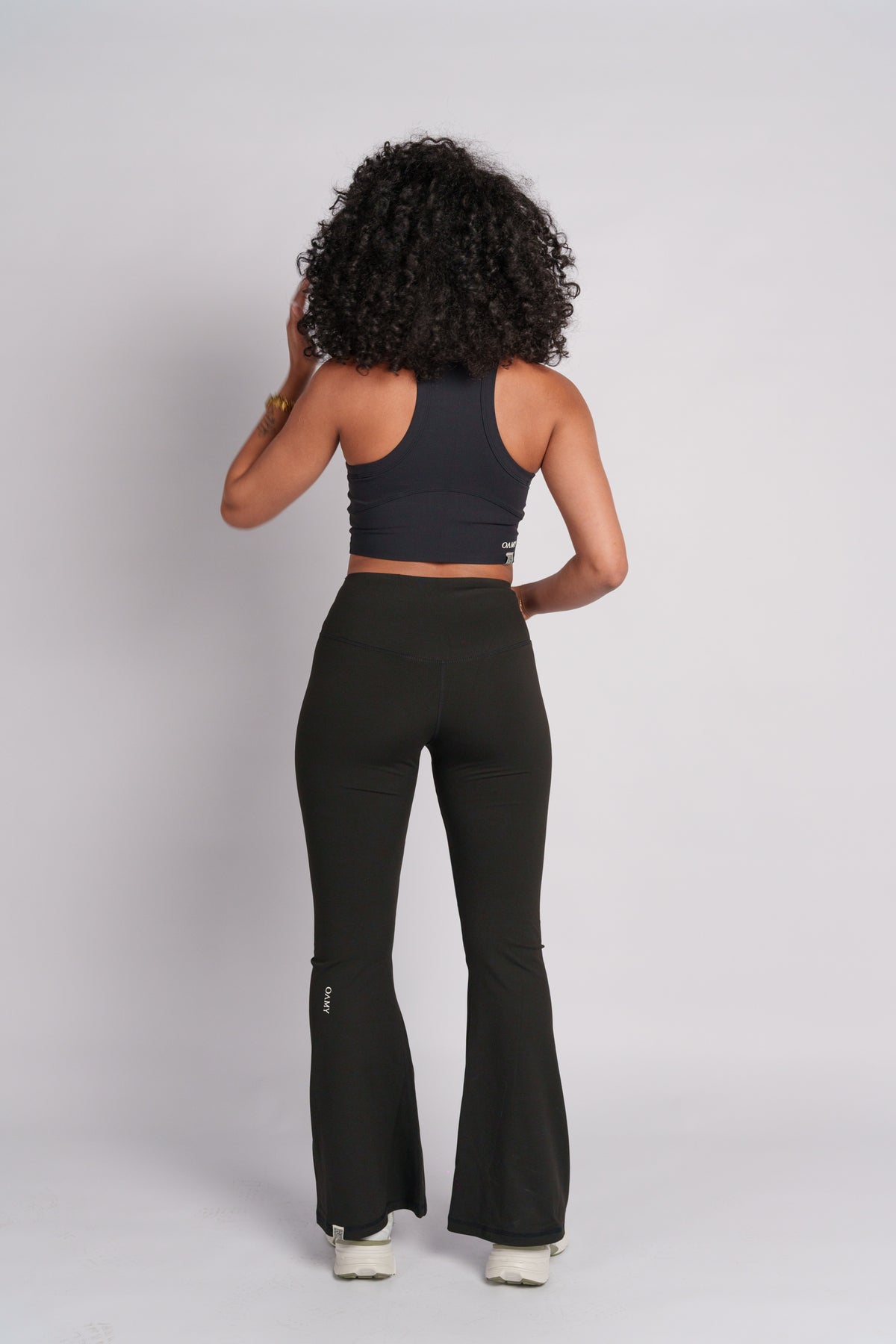 Woman wearing a black crop top with black flared pants.