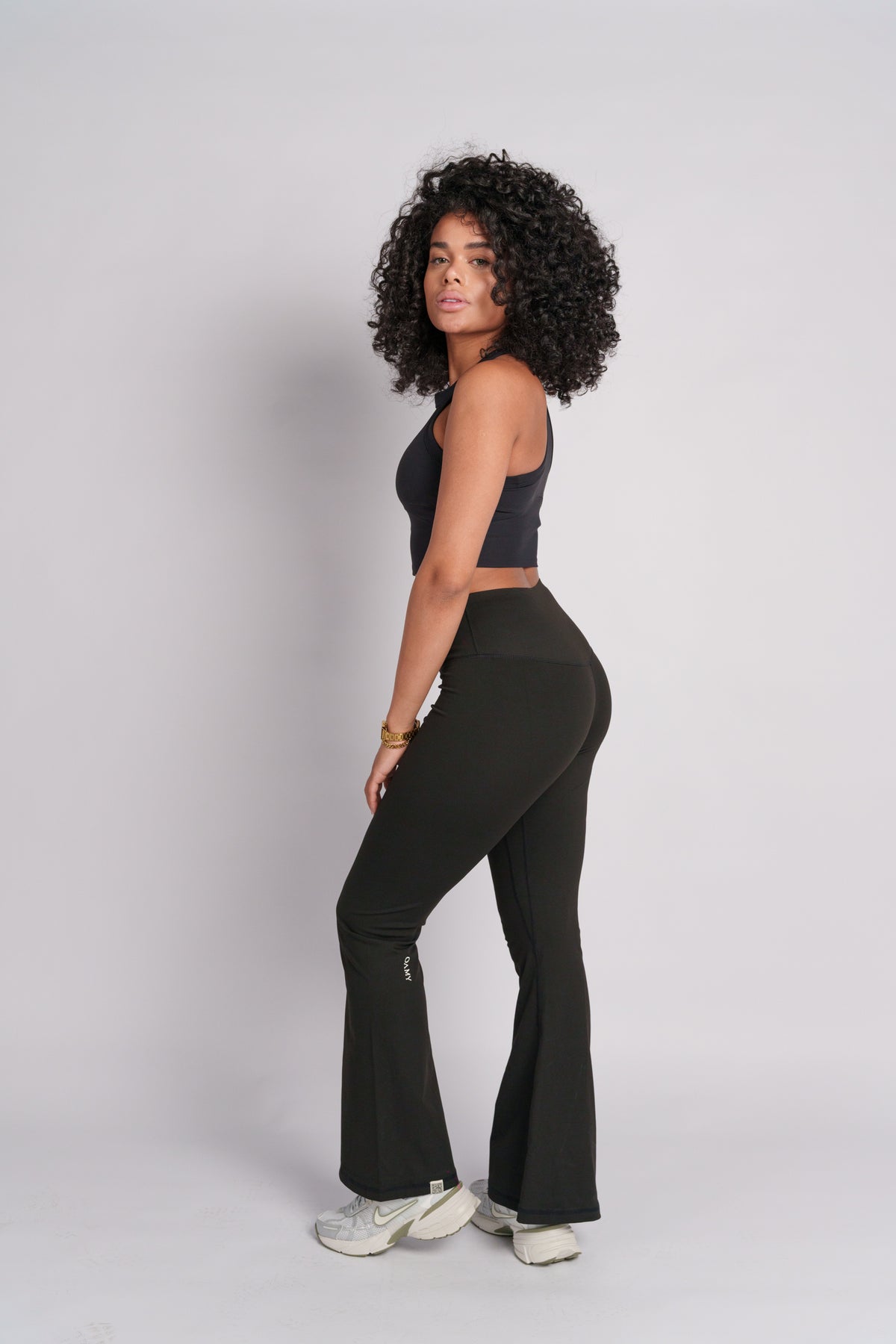 Woman wearing a black crop top with black flared pants.