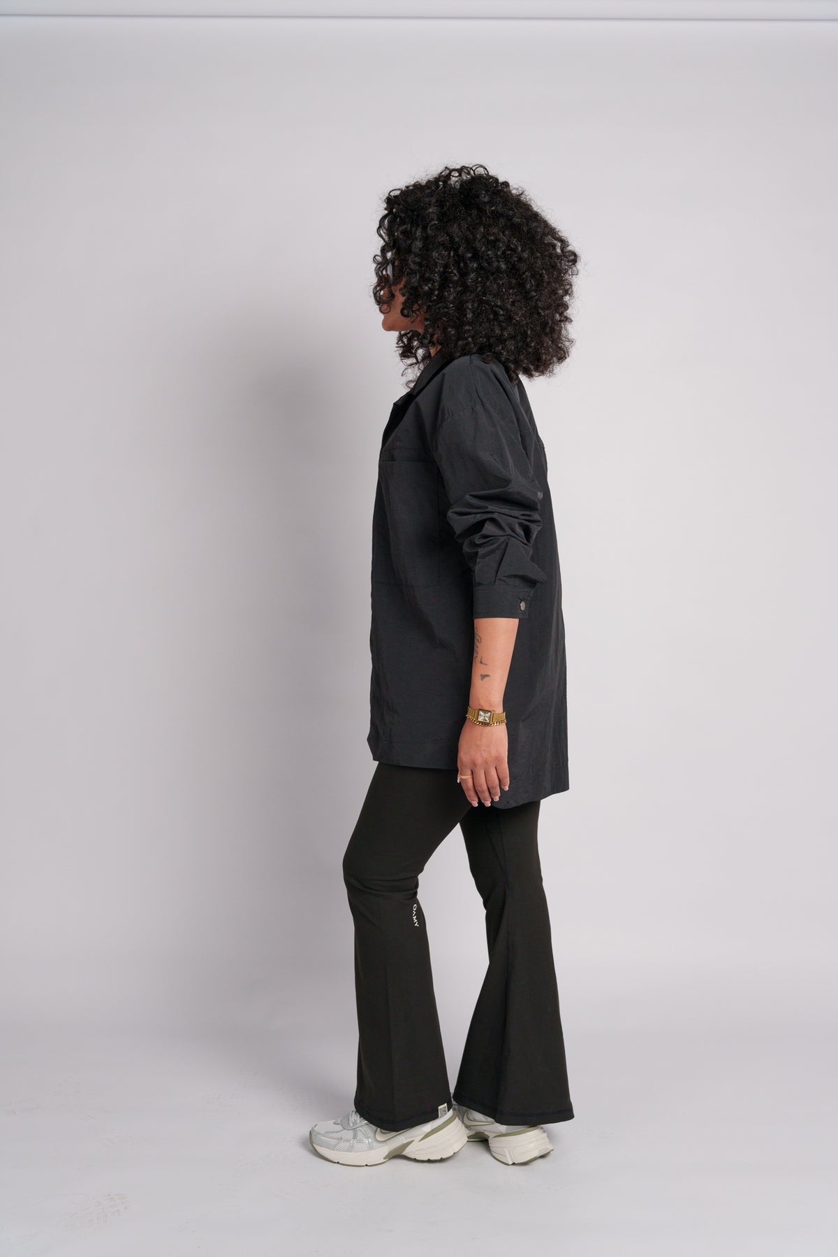 Woman wearing a black crop top with black flared pants and black shirt.