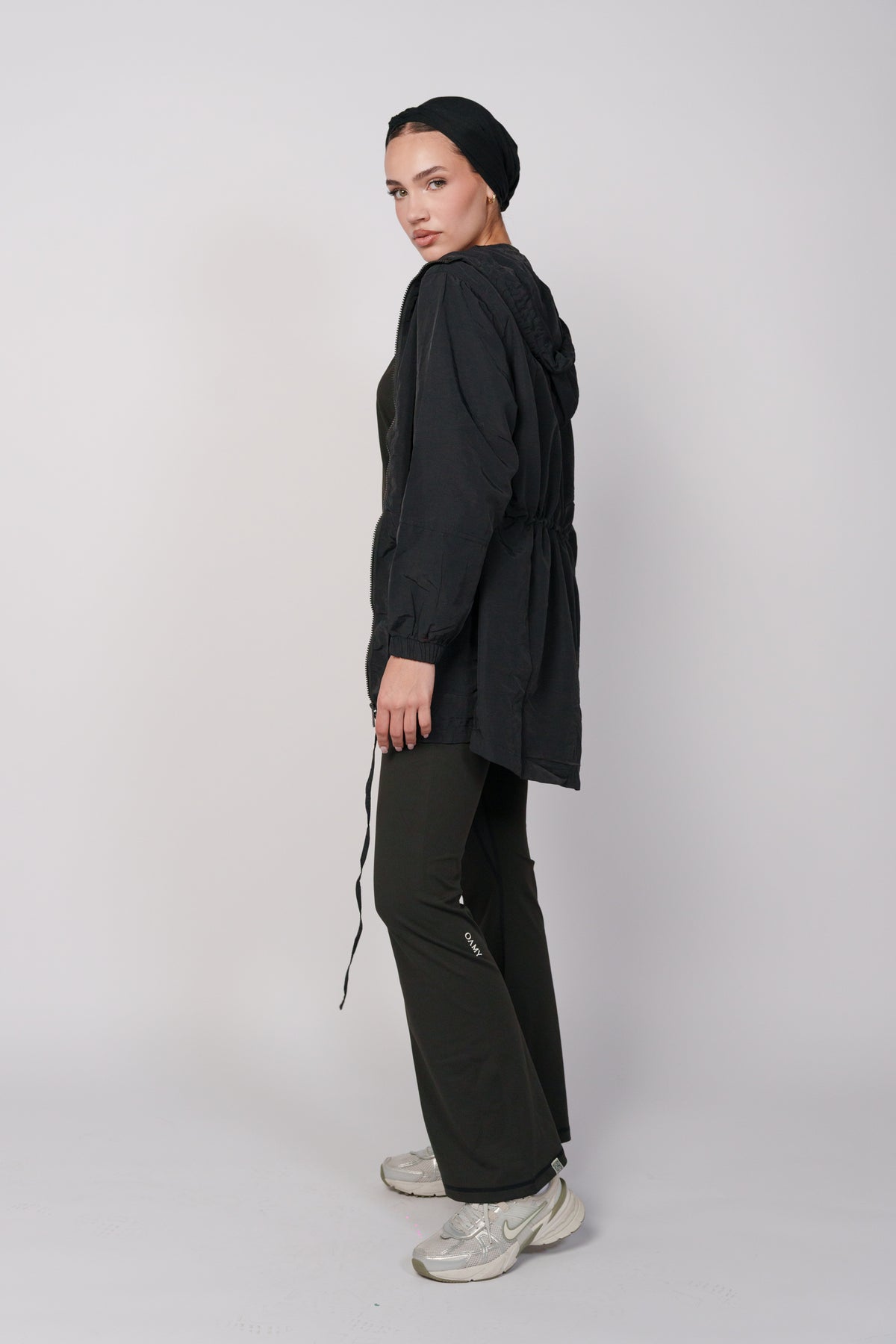 Woman wearing a black jacket with a hood and a black flared pant.