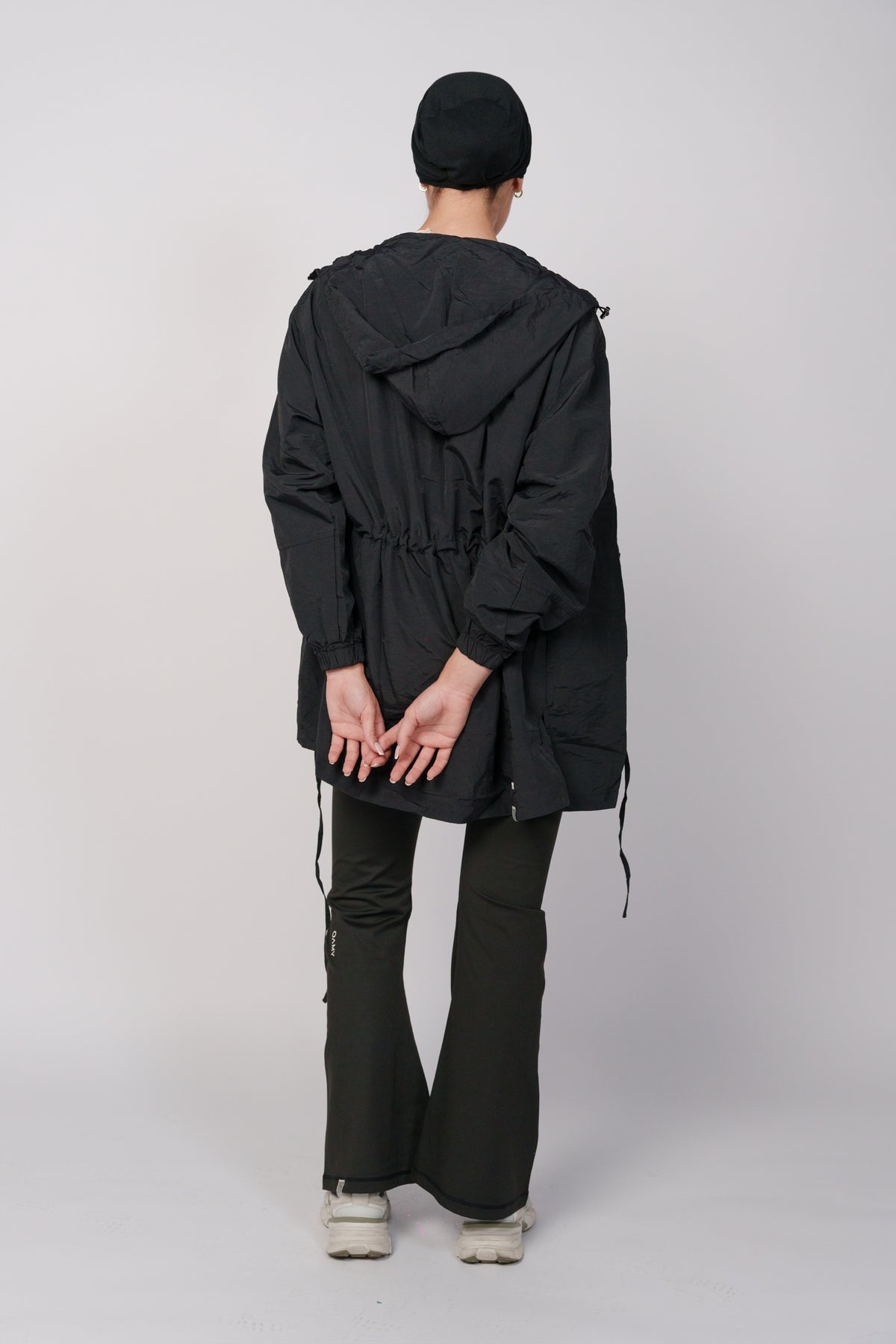 Woman wearing a black jacket with a hood and a black flared pant.