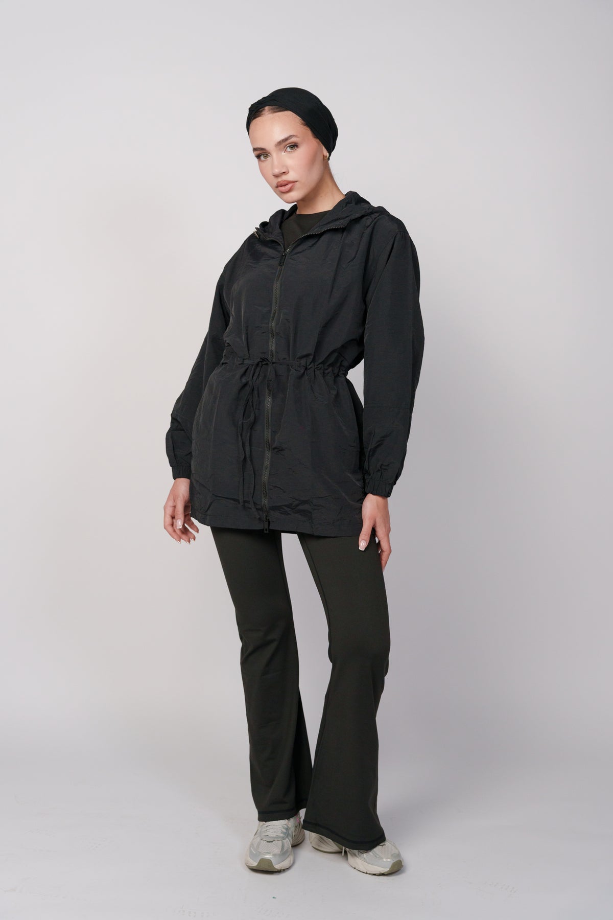 Woman wearing a black jacket with a hood and a black flared pant.