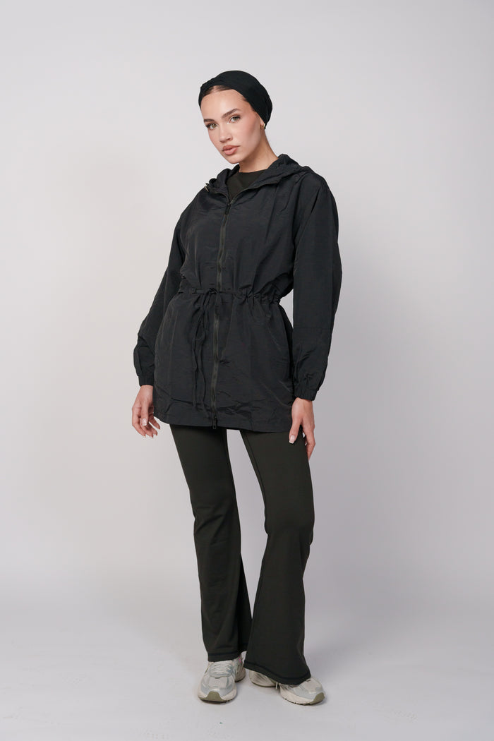 Woman wearing a black jacket with a hood and a black flared pant.