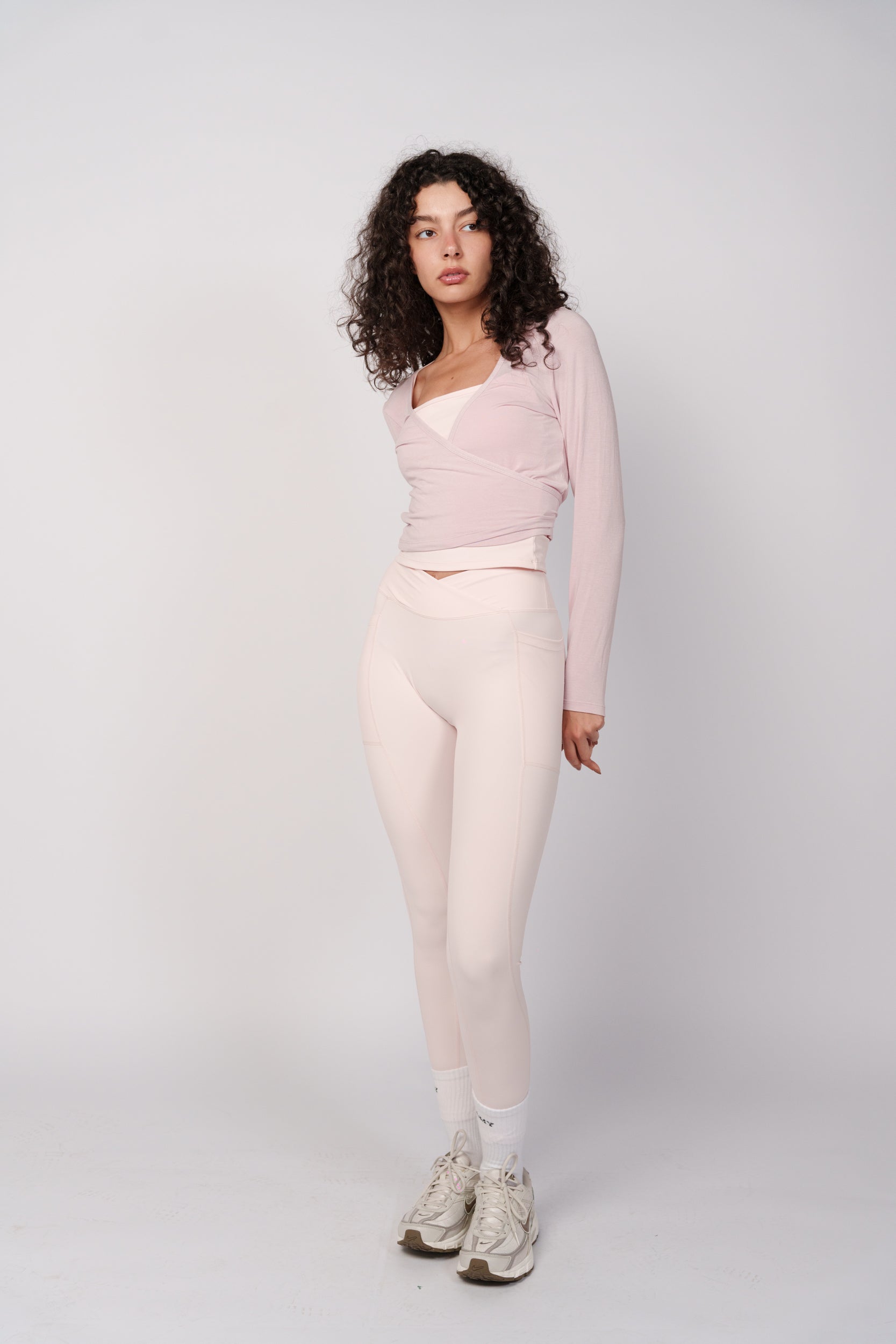 Woman wearing a light pink long-sleeve top and pants on a white background