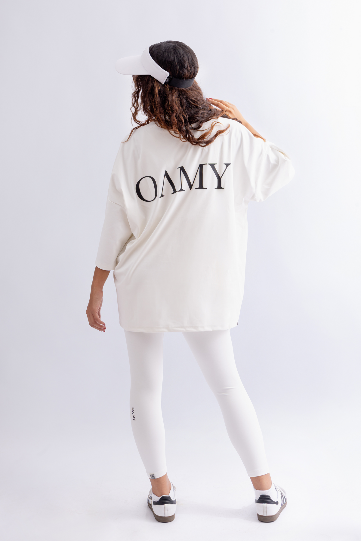 Model wearing the OAMY Super Oversized Soft Skin T-Shirt in White with black Cargos and a black headscarf, holding a black tote bag.