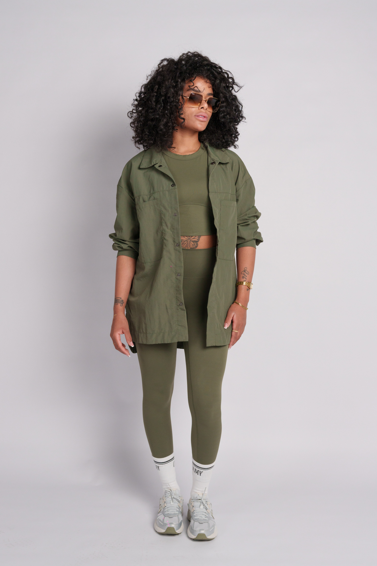 Woman wearing an olive shacket with olive leggings and olive crop top.