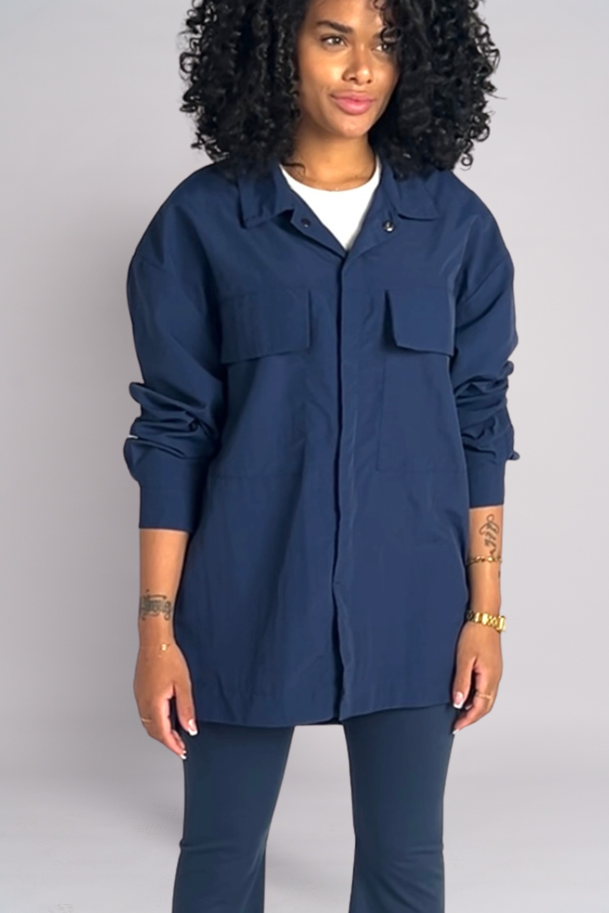 Woman wearing a navy blue jacket and pants on a plain background