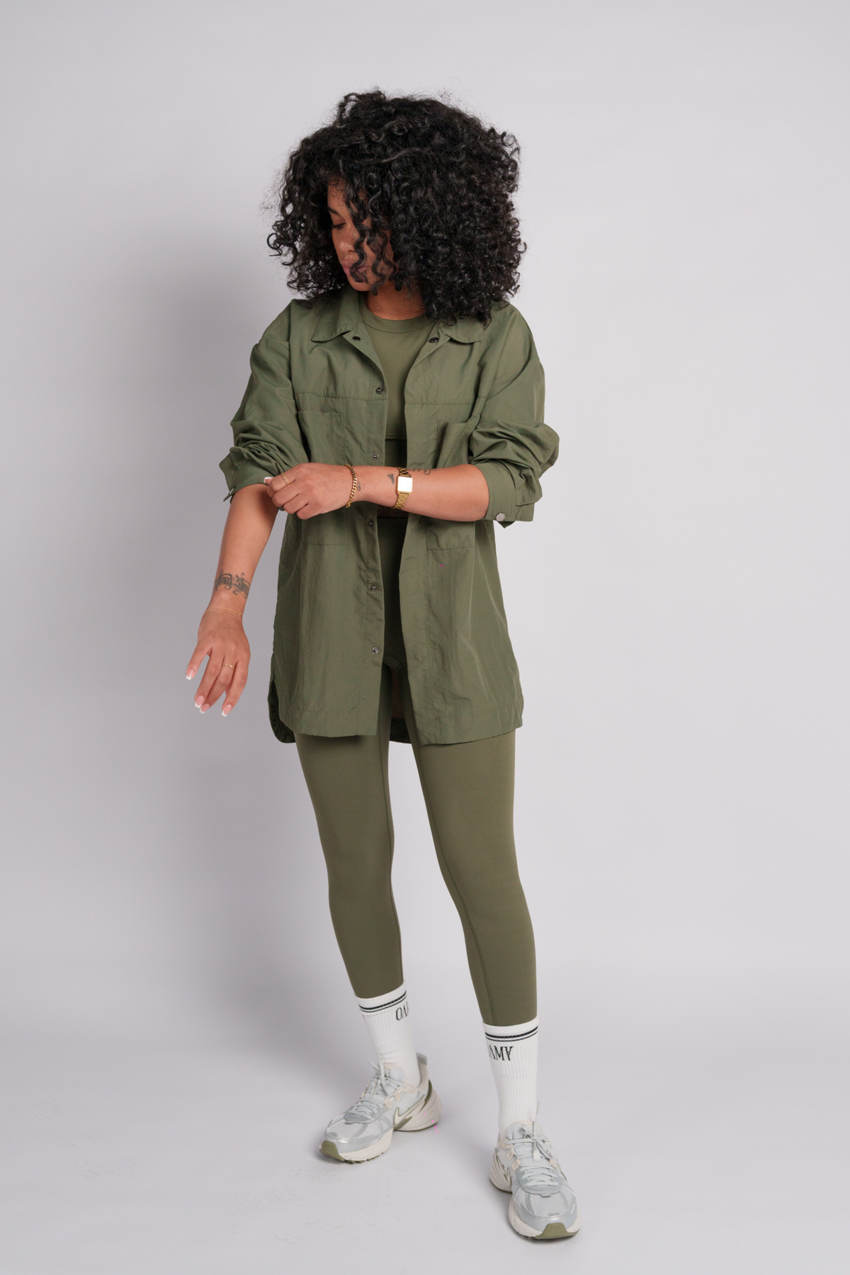 Woman wearing an olive shacket with olive leggings and olive crop top.