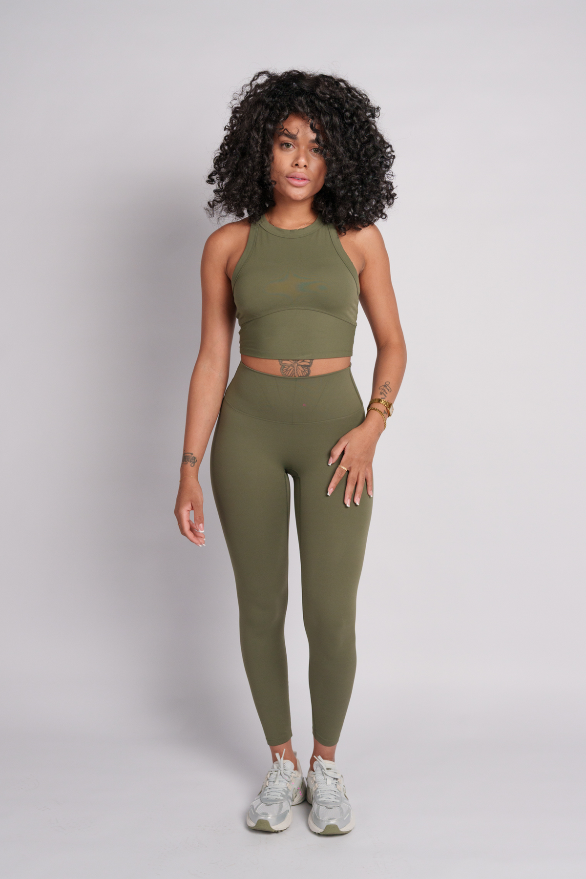 Woman wearing an olive green crop top with leggings.