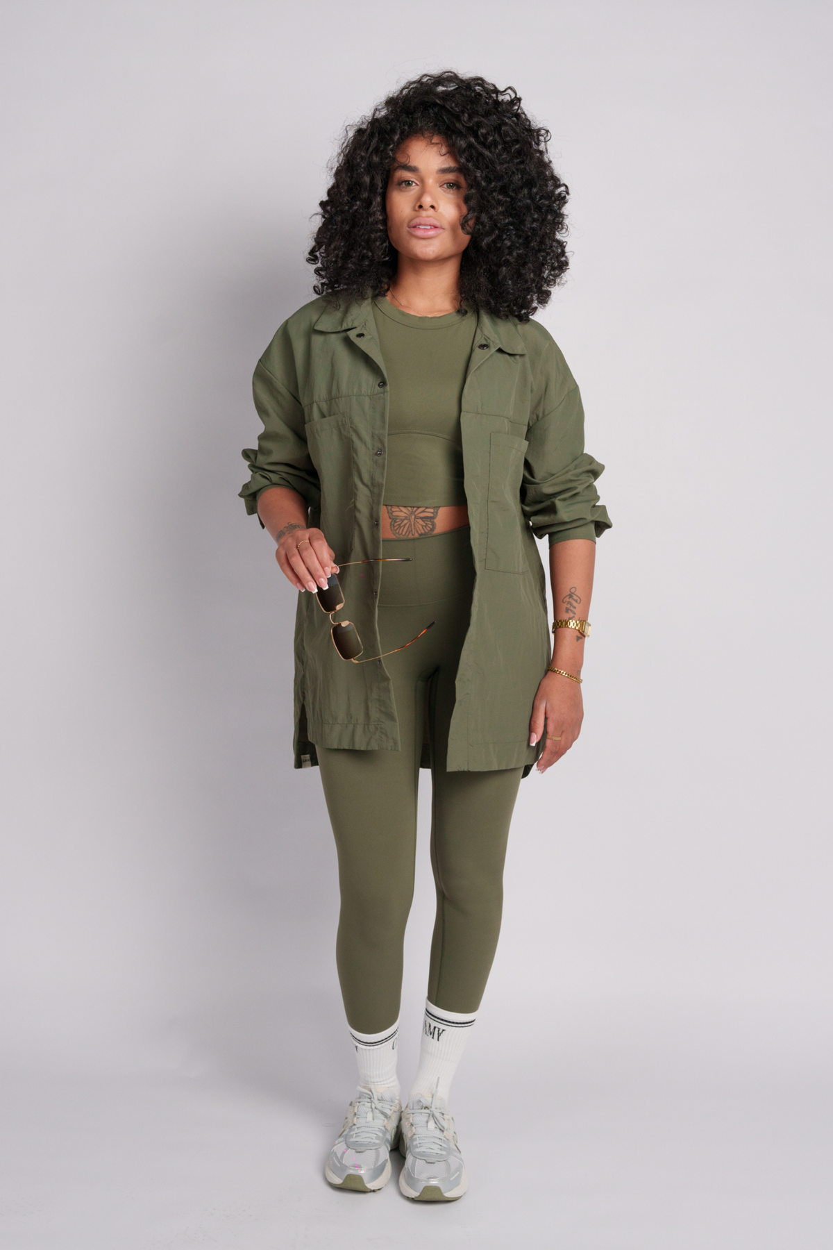 Woman wearing an olive green shirt with olive crop tops and leggings.
