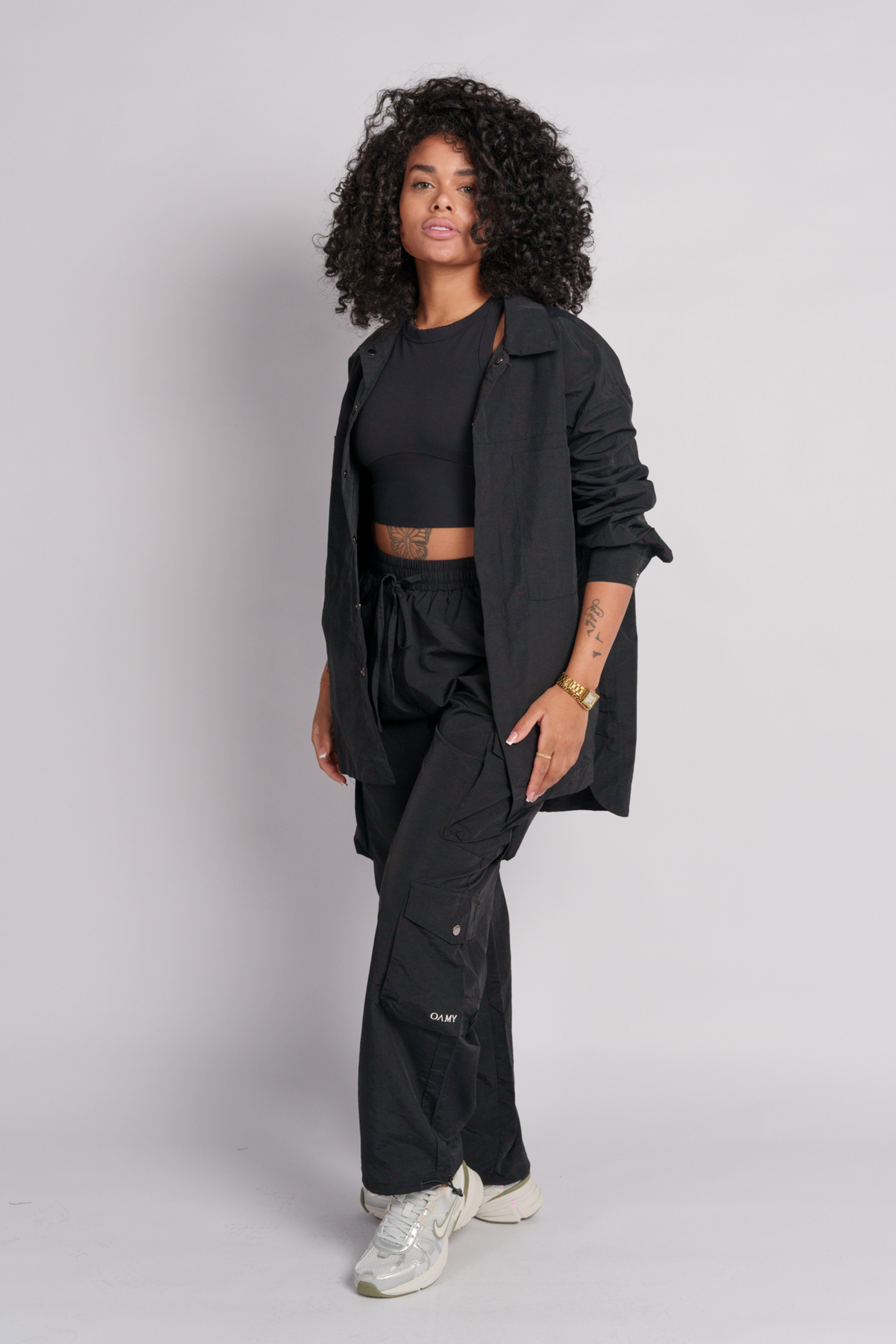 Person wearing a black shirt with a black cargos and a black crop top.
